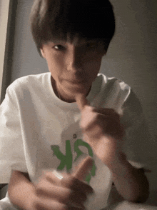 a person wearing a white t-shirt with a green letter sk on it