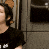 a woman wearing a black shirt that says s et is sitting in front of a television
