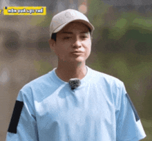 a man wearing a hat and a blue shirt is standing in front of a green background .