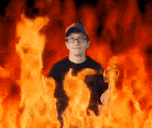a man wearing glasses and a blue hat is surrounded by flames