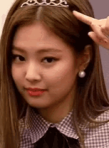a close up of a woman wearing a tiara on her head and earrings .