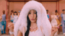 a woman wearing a white fur hood is standing in front of a crowd .