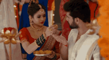 a man and a woman are standing next to each other and the woman is feeding the man some food