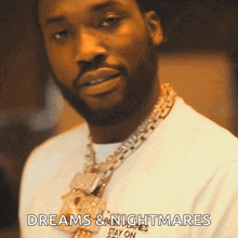 a man with a beard is wearing a white shirt and a gold chain .