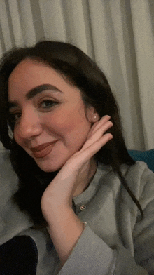 a woman with her hand on her face is smiling for the camera