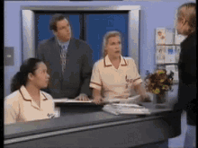 a man in a suit and tie is standing behind a counter with two nurses