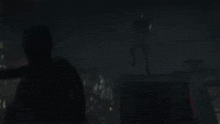 a silhouette of a person in a dark room with a city in the background