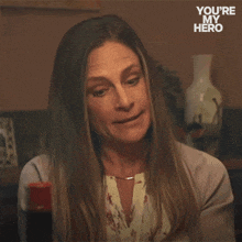 a woman says just peachy in front of a you 're my hero poster
