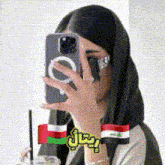 a woman is taking a selfie with her phone while holding a drink .
