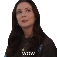 a woman wearing a grey sweater and a necklace has the word wow on her face