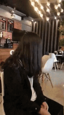 a woman in a black jacket is sitting in a room