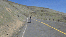 a man wearing a black shirt and a helmet is riding a bike down a road
