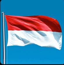 a red and white flag is flying in a blue sky