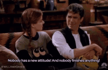 a man and a woman are sitting on a couch and the woman says nobody has a new attitude