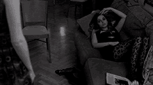 a woman is laying on a couch in a living room with a magazine in her hand .