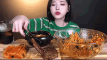 a woman is sitting at a table with a bowl of food and a bowl of rice