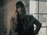 a woman talking on a cell phone with a pendant that says t.i. on it