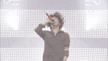 a man is singing into a microphone in front of a wall of dots