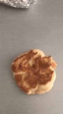 a piece of bread is sitting on a gray surface .