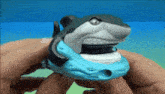 a person is holding a toy shark in their hand