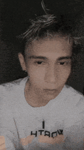 a young man wearing a white shirt that says htaow on it