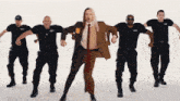 a man in a suit and tie is surrounded by security guards wearing shirts that say security