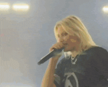a woman is singing into a microphone in a dark room .