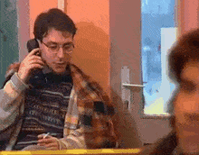 a man is talking on a cell phone while sitting at a table
