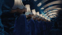 a row of people standing in a tunnel with lampshades on their head