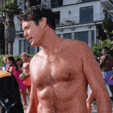a man without a shirt is standing in front of a building