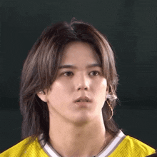 a man with long hair wearing a yellow jersey making a funny face