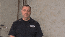 a man wearing a blue shirt with a sticker on it that says ' a & a '