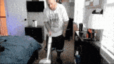 a man is using a vacuum cleaner in his bedroom