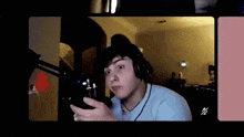a man wearing headphones and a blue shirt is holding a microphone and looking at the camera