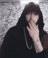 a man with a tattoo on his wrist wearing a black hoodie