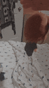 a person is holding a black object on a bed with dinosaurs on it