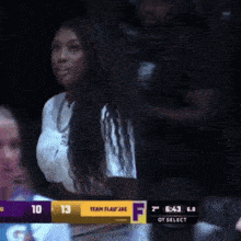 a woman in a white shirt stands in front of a scoreboard that says team flair jae