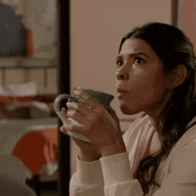 a woman is holding a cup of coffee and making a surprised face