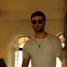 a man wearing sunglasses and a white shirt is standing in a room