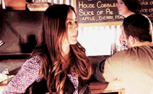 a woman standing in front of a sign that says slice of pie