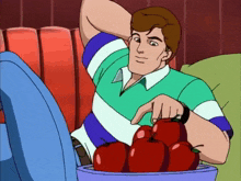 a man in a striped shirt sits on a couch with a bowl of apples
