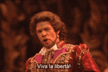 a man in a red and gold costume sings viva la liberta