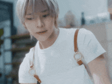 a close up of a person wearing a white t-shirt and brown straps