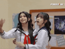 two girls are standing next to each other in front of a bulletin board that says freefire