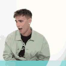 a young man wearing a green jacket and a black shirt that says a man