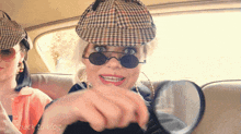 a woman wearing a hat and sunglasses is holding a magnifying glass with the words back to vlog written on the bottom