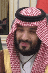 a man wearing a red and white checkered head scarf smiles