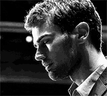 a black and white photo of a man with a beard and a serious look on his face .
