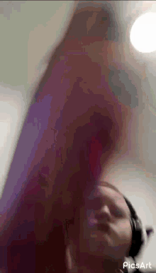 a blurry picture of a person wearing headphones and a purple shirt taken by picsart