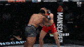 two fighters are fighting in a cage with a manscaped banner behind them